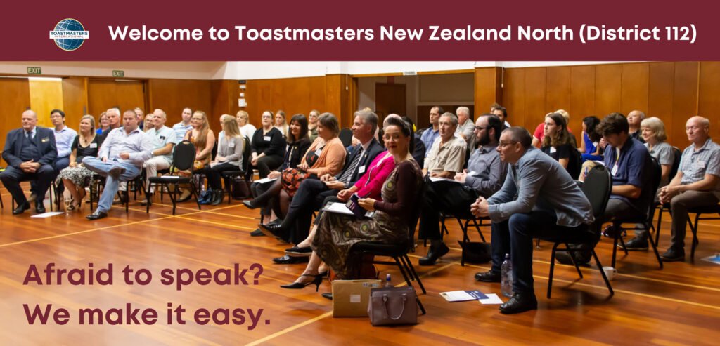 A large group of Toastmasters in a hall, listing attentively