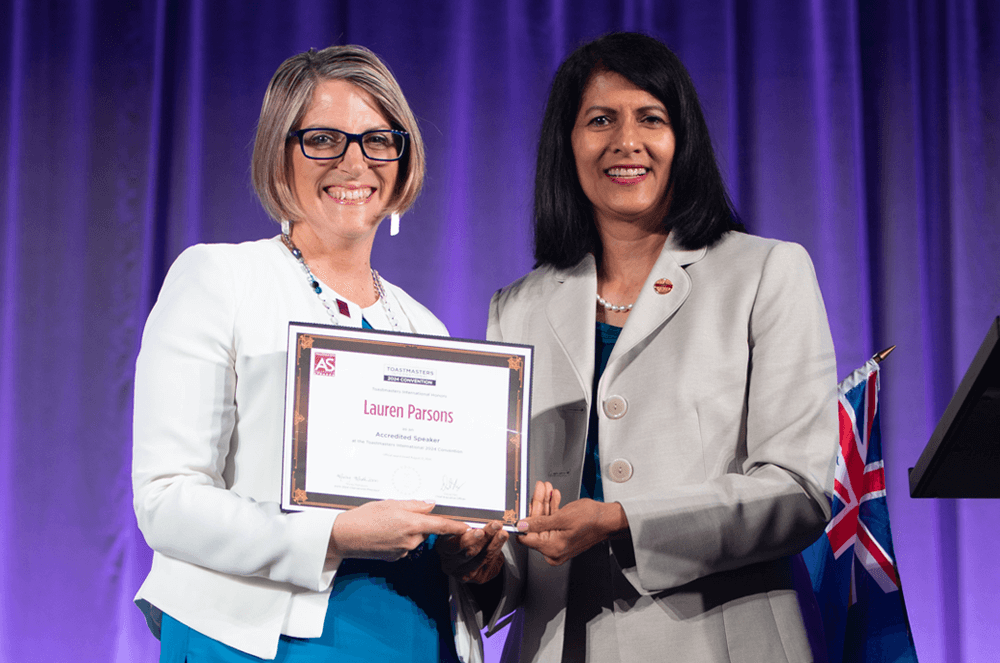 Lauren Parsons DTM receives her Accredited Speaker certificate from Toastmasters International President Radhi Spear